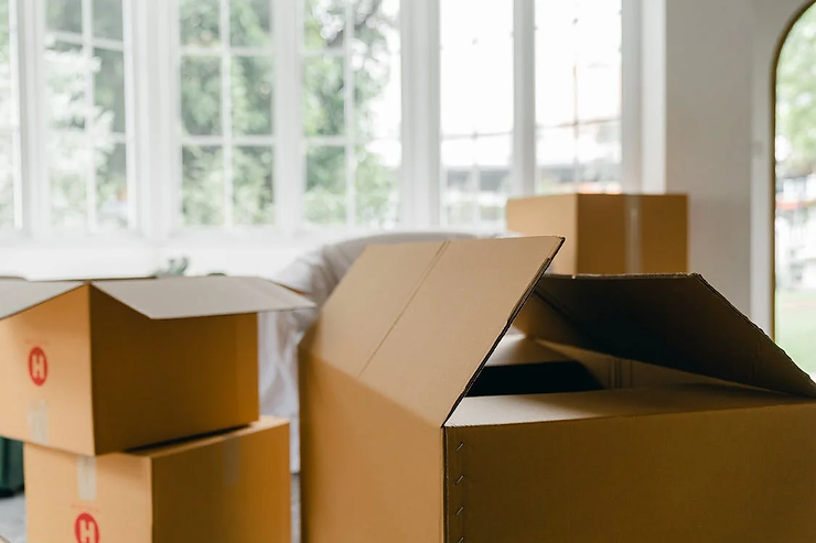 Cardboard moving boxes stacked in a bright, empty living room