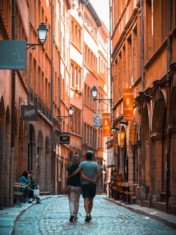 Couple walking down a narrow European alleyway with orange buildings
