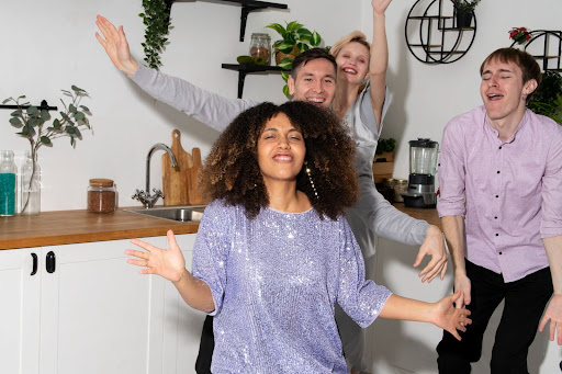 Group of cheerful friends dancing together in a bright kitchen