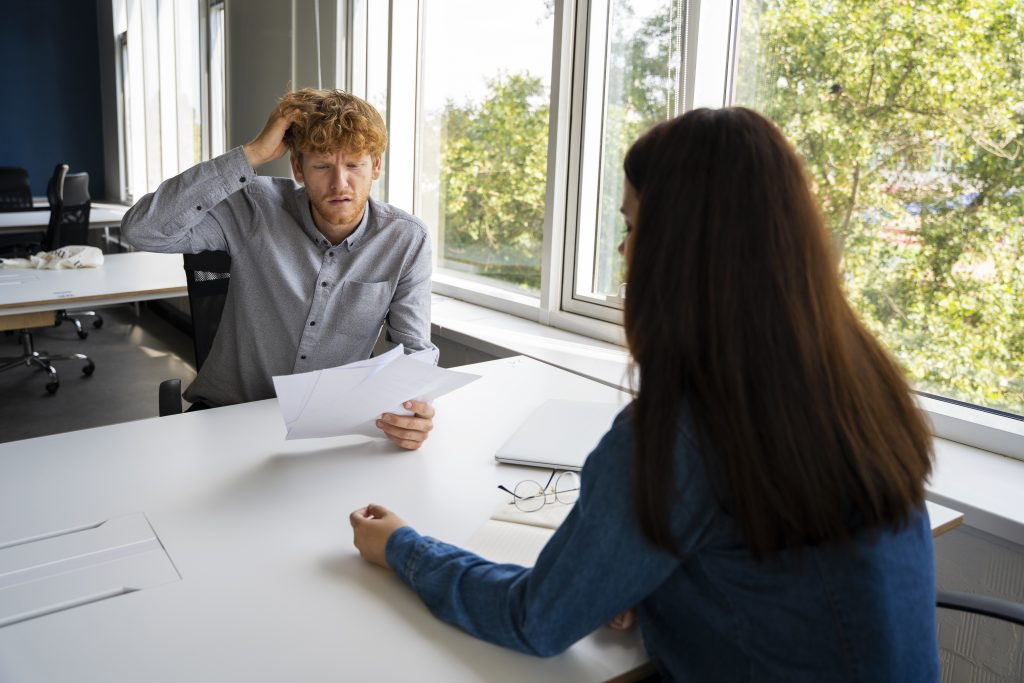 Confused man scratching his head while reviewing papers with consultant